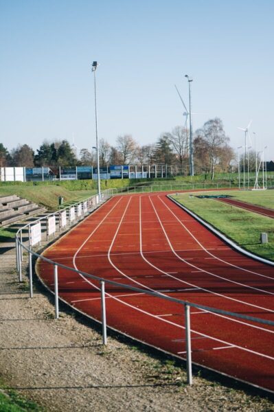 A red running track curves under a clear blue sky.