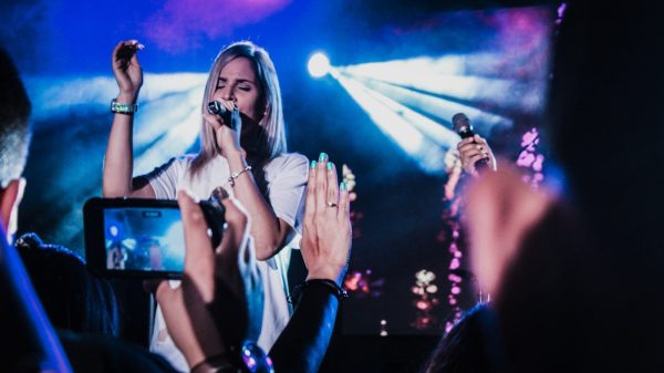 woman in white shirt singing on stage