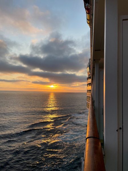 The sun is setting over the ocean as seen from a ship