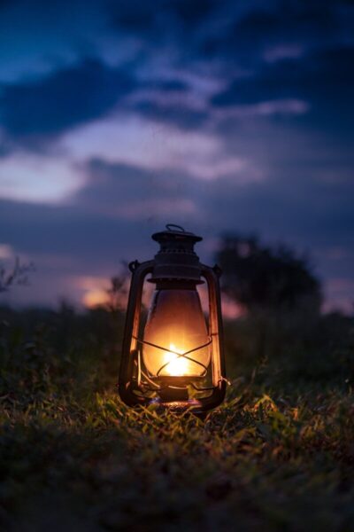A lit lantern sitting in the middle of a field